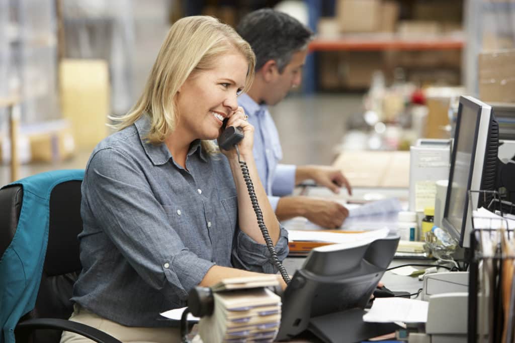 Businesswoman Working At Desk In Warehouse Businesswoman Working At Desk In Warehouse